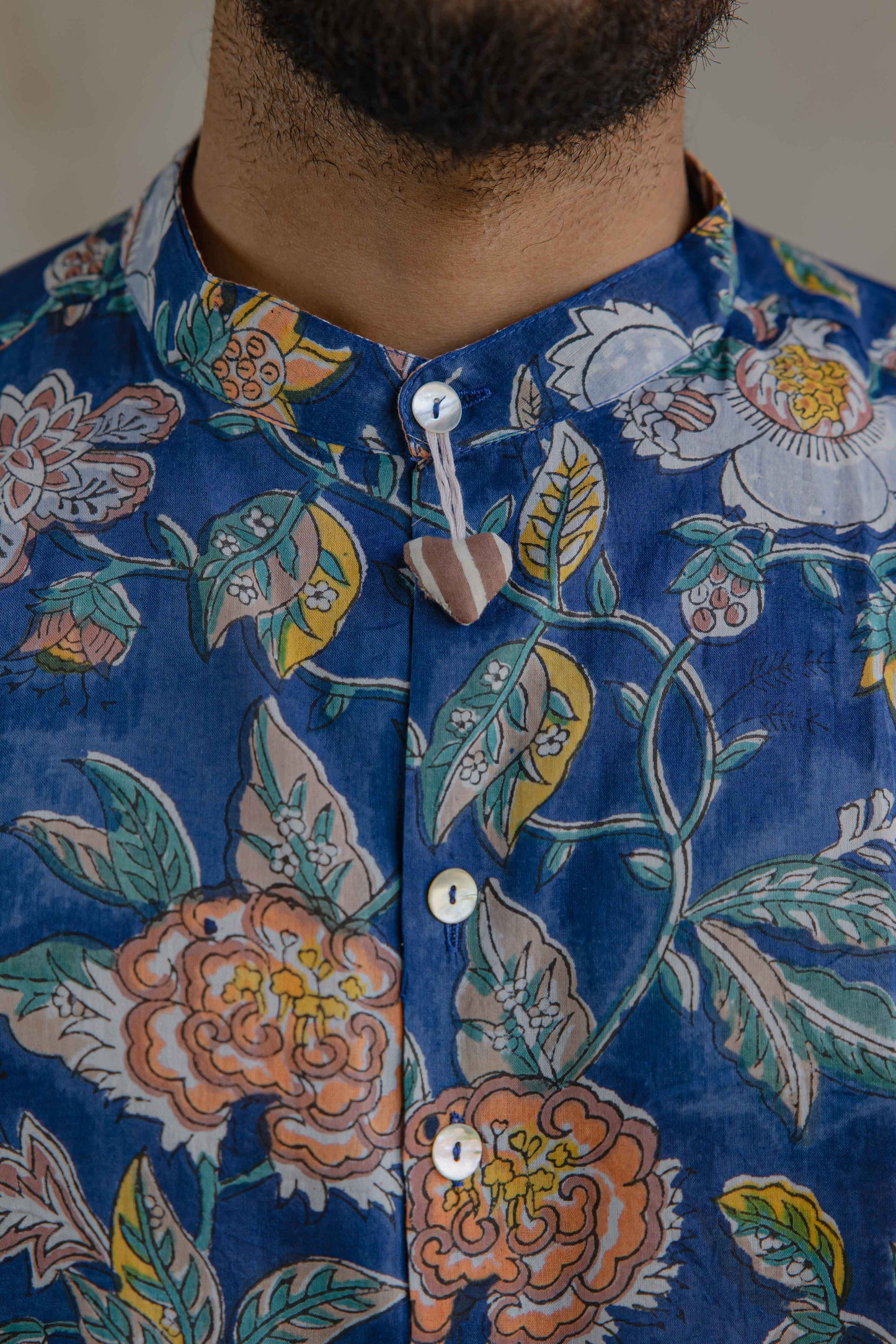 Stuffed heart button hanging on the shell inspired buttons of Wildflower floral summer shirt